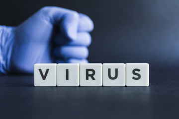Fight against virus. Letter blocks with a fist with protective glove as the backdrop.