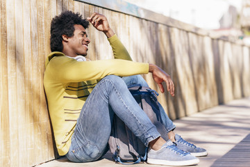 Black man with afro hair and headphones resting on the ground.