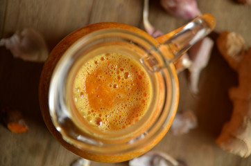 Orange and garlic drink for flu in a glass jug on a wooden background
