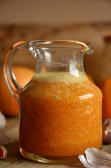 Orange and garlic drink in a glass jug on a wooden background