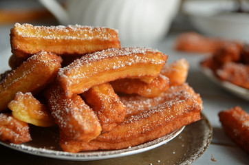 Fresh churros sprinkled with powdered sugar on a plate