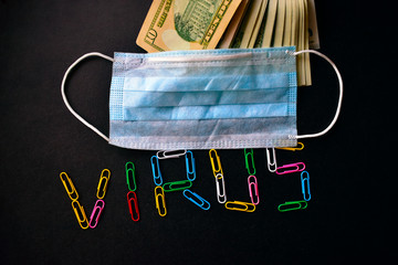 Lettering with multicolored paper clips virus on a black background and a protective medical mask