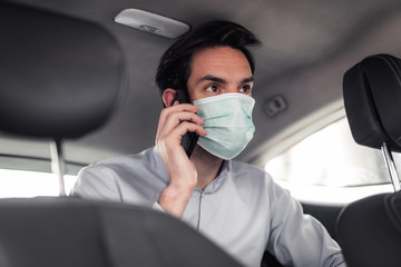 Man with protective mask and having chat on his mobile and traveling in car.
