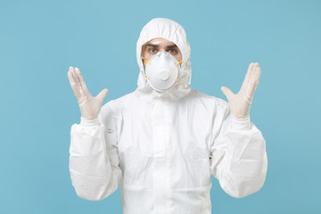 Man in white protective suit respirator mask isolated on blue background studio. Epidemic pandemic new rapidly spreading coronavirus 2019-ncov originating in Wuhan China, medicine flu virus concept.