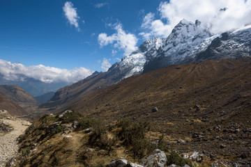 Fototapeta na wymiar Rocky paths and green valleys surrounded by snowcapped mountains on the Salkantay Trek, Peru