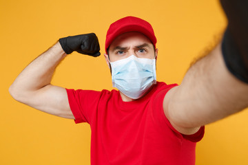 Close up delivery man in red cap blank t-shirt uniform sterile face mask gloves isolated on yellow background studio Guy employee doing selfie shot Service pandemic coronavirus virus 2019-ncov concept