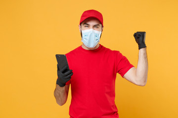 Delivery man in red cap blank t-shirt uniform sterile face mask gloves isolated on yellow background studio Guy courier hold mobile cell phone Service quarantine pandemic coronavirus 2019-ncov concept