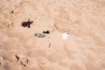 Debris from plastic bottles and bags lies on the sand