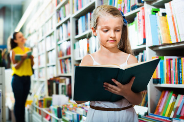 Small girl in school age standing with open book