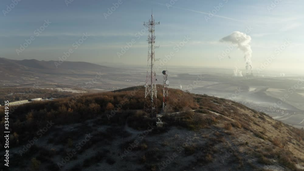 Wall mural communication transmitter tower on a hill in the countryside aerial view drone footage. cellphone ne