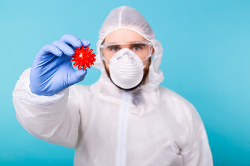 Covid-19, Vaccine development and medicine concept - Man scientist or doctor dressed personal protective equipment and holding a model of coronavirus.
