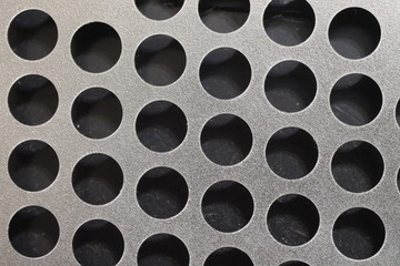 Round holes in a silver sheet of metal.