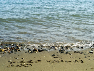 Blue sea and words on beach sand