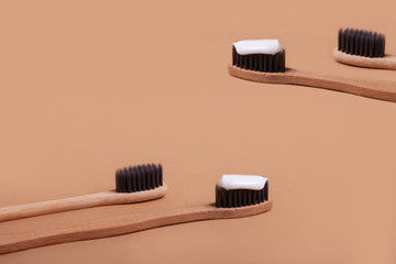 A row of wooden toothbrushes on a brown background.