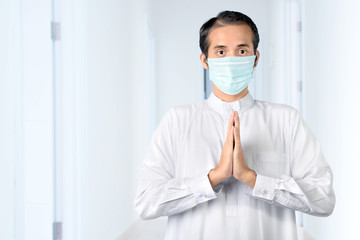 Fototapeta na wymiar Asian Muslim man wearing flu mask standing and praying