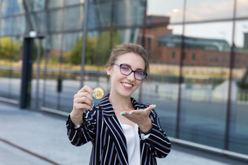 The young beautiful woman holds bitcoin in a hand.