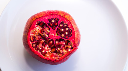 Juicy, fresh, ripe fruit on a plate. Pomegranate with a chopped top. Proper nutrition, freshly squeezed juices.
