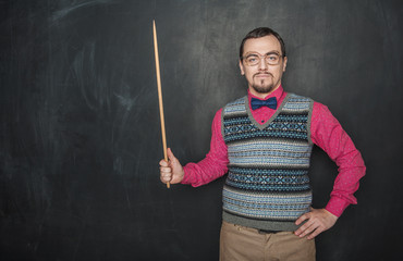Serious business man or teacher retro style with pointer on blackboard
