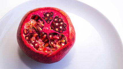 Juicy, fresh, ripe fruit on a plate. Pomegranate with a chopped top. Proper nutrition, freshly squeezed juices.