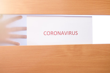 Kwarantanna w domu z powodu Coronavirus, zamknięte dzrzwi i notatka. Widoczne dłonie © andsko