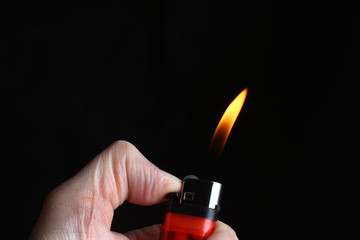 a burning torch from a lighter in the hands on a black background - Powered by Adobe