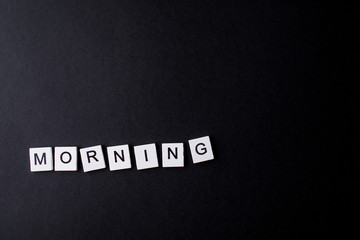 A word in the morning from small white wood squares on a black background.