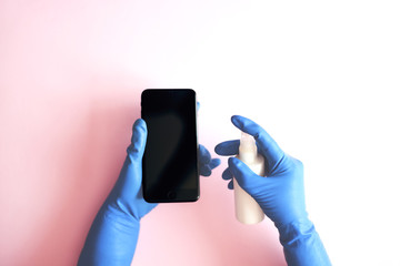 Disinfection in medical gloves of a smartphone with an antiseptic spray.