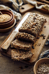 Gluten-free homemade buckwheat bread with the addition of various seeds cut into slices on a wooden board close up