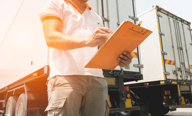 Truck driver holding clipboard inspecting safety vehicle maintenance checklist a truck trailer,...