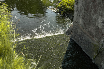 Waste water flows through a concrete channel into the lake