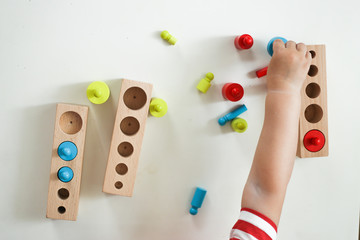 child plays with a developmental toy. boy plays with wooden cylinders and sorting by size. The concept of educational toys. The development of fine motor skills, imagination and logical thinking