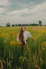 Portrait of a girl in a vintage dress on nature background. A girl with long hair in a field on a summer sunny day. Fashion vintage dress.
