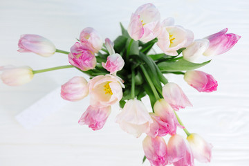 Obraz na płótnie Canvas Tulip flowers in glass vase with gift card over white background isolated