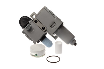 Steel compressed air filter with on off know with attached silencer next to a spare parts kit containing grease, gasket and air filter part, isolated on white background