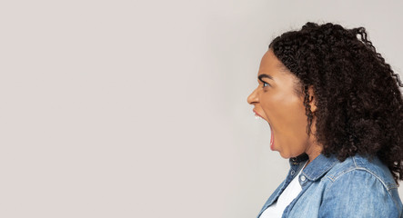 Angry african american woman screaming with rage at copy space - Powered by Adobe