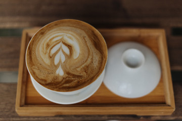 cup of coffee with cream on wooden background