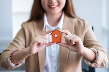 Female holding a house model for family home and real estate.