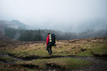 Obraz premium Senderista caminando por el monte en un día con niebla y árboles al fondo