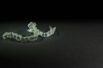 Close-up view of two insulated transparent dental braces on a black background. Concept of a dental brace.