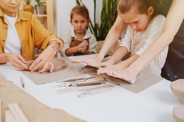 Children and adults engaged together at the table, modeling from clay