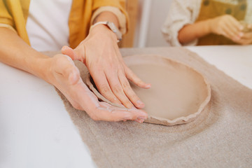 Obraz na płótnie Canvas close-up of women's hands, she modeling a plate