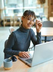 Portrait smart young woman in eyeglasses smiling to camera, enjoying studying in coworking space,...