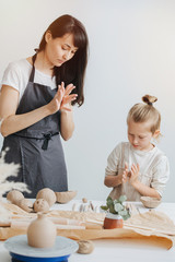 Naklejka premium Adult and child in aprons are sculpting together