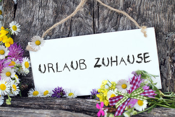 Schriftzug, Urlaub zuhause, auf weisser Tafel, in der Natur geschrieben.
