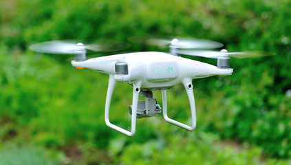 White drone with camera flying in the spring countryside