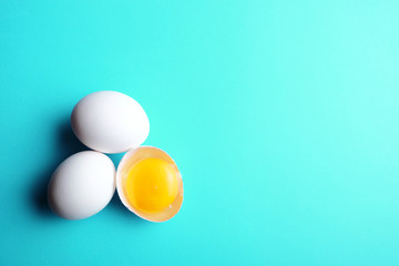 Three eggs with one broken on aquatic blue background. Group of three eggs.
