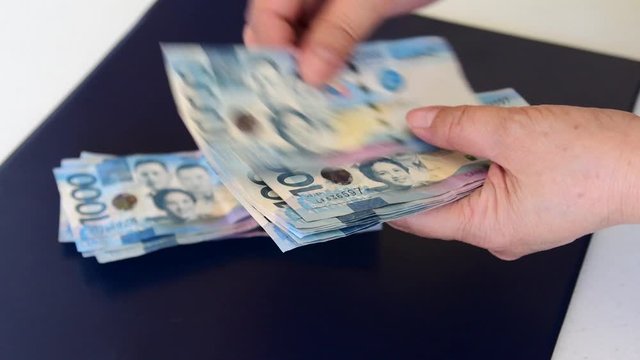 Counting a bulk of 1000 Philippine peso cash on a table by hand