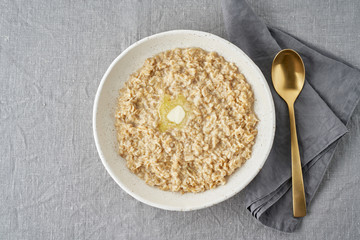 Whole oatmeal, large bowl of porridge with butter for breakfast, morning meal.