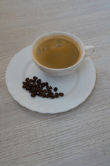 Top view of a cup of coffee and coffee beans on white plate