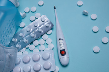 thermometer and pills on medical blue background as a coronavirus concept